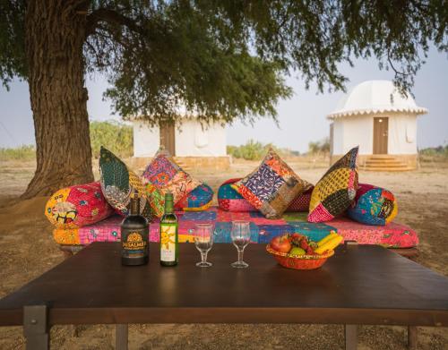 斋沙默尔Sonal Desert Camp Jaisalmer的一张桌子上带酒瓶和玻璃杯的沙发