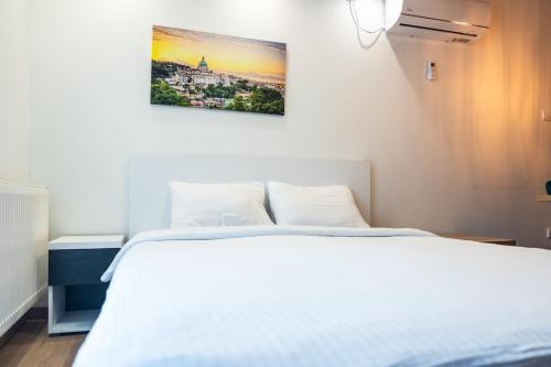 诺维萨德Daisy resort的卧室配有一张白色床,墙上挂着一幅画