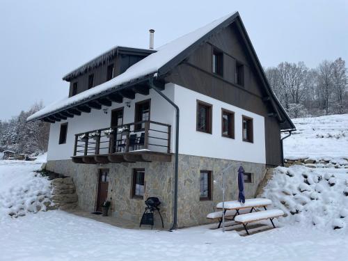 PlavyChalupa Jizerka的雪地中的一座建筑,前面有两英尺长