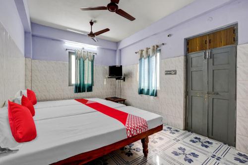 蒂鲁帕蒂OYO Flagship Sai Ganesh Deluxe Lodge的一间卧室配有一张带红色枕头的床和一扇门