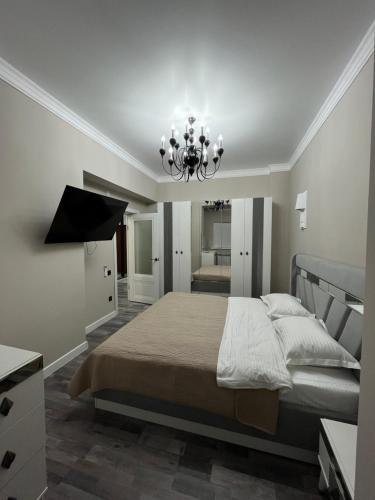 阿克托比Рахат апарт的一间卧室配有一张大床和一个吊灯。