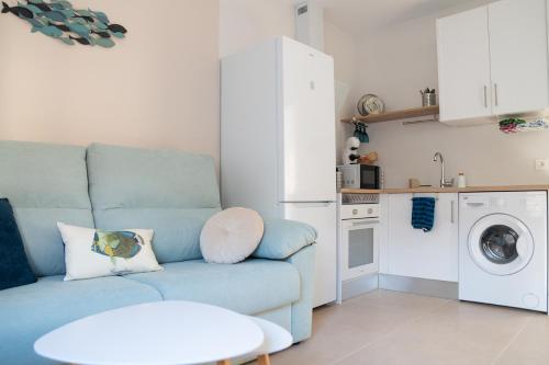 马萨龙港Apartamentos Barlovento的一间带蓝色沙发的客厅和一间厨房