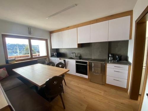 安特尔莫伊亚Ampio appartamento di 200mq nel cuore di Antermoia的厨房配有白色橱柜和木桌