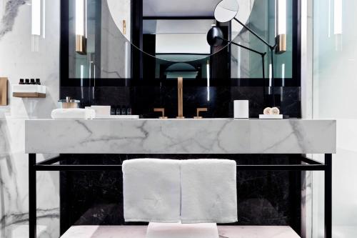 雅典Academias Hotel, Autograph Collection的一间带大理石台面和镜子的浴室