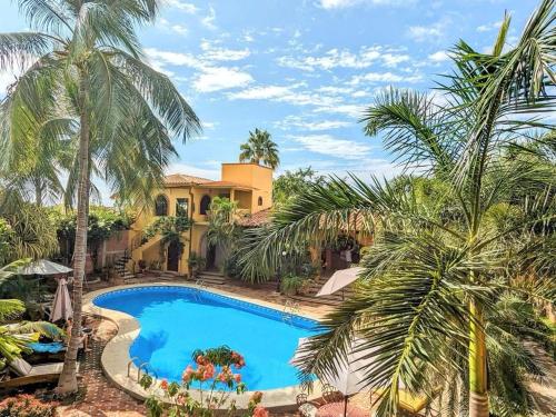 埃斯孔迪多港拉哈西恩德套房酒店的棕榈树屋前的游泳池