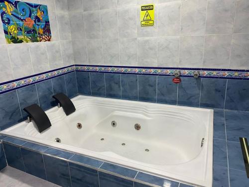 波哥大Hotel Yolima Real的蓝色瓷砖浴室设有大浴缸