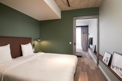 巴德胡弗多普Corendon Apartments Amsterdam Schiphol Airport的卧室设有一张白色大床和绿色的墙壁