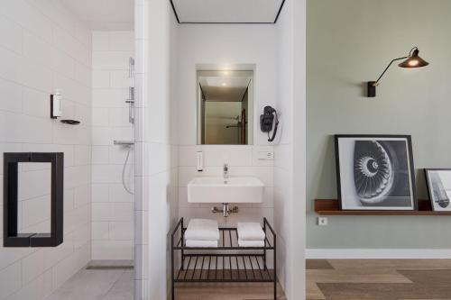 巴德胡弗多普Corendon Apartments Amsterdam Schiphol Airport的白色的浴室设有水槽和镜子