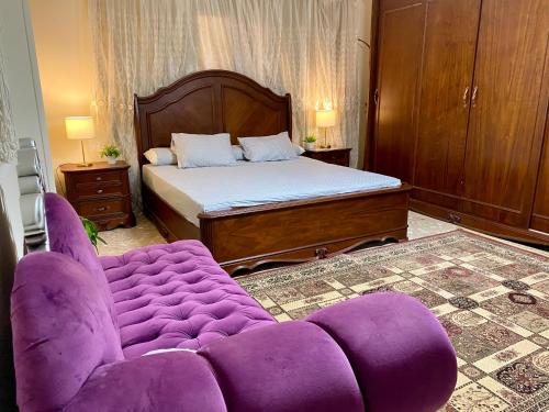 开罗Cozy 3BR Apartment in Maadi的一间卧室配有一张紫色的沙发和一张床
