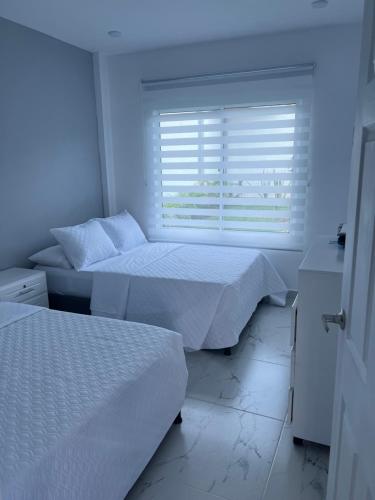 GiganteCompostela Cabañas Gigante的白色客房的两张床,设有窗户