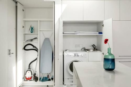 悉尼EIGHT TWO NINE TWO VI: BONDI BEACH的白色的厨房配有洗衣机和一个位于柜台上的花瓶