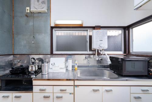 东京GuestHouse　YOU&I平和島的厨房配有水槽和微波炉