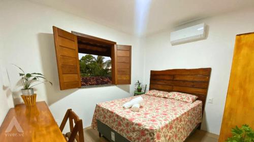 盖比姆Viva Guaibim: Casa de Praia com Piscina e Churrasqueira的一间卧室配有一张床、一张桌子和一个窗户。