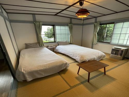 小樽Otaru - House - Vacation STAY 15278的一间卧室设有两张床、一张桌子和窗户。