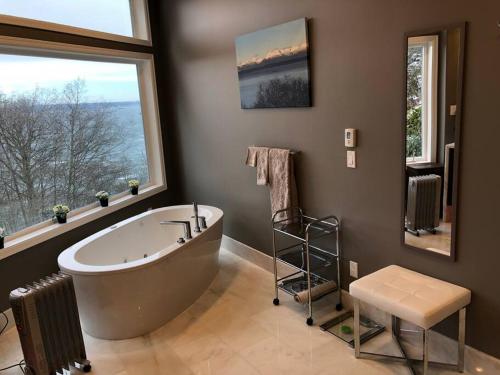 西雅图Romantic Spacious Suite with Salish Sea & Mountain Views at Seattle Luxury Estate的大型浴室设有大浴缸和2扇窗户。