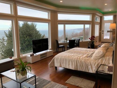 西雅图Romantic Spacious Suite with Salish Sea & Mountain Views at Seattle Luxury Estate的一间卧室配有一张床,另一间设有窗户。