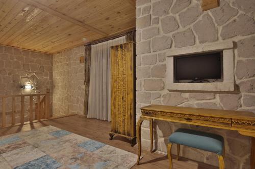于尔居普ELEVRES STONE HOUSE HOTEL的客厅设有壁炉和石墙上的电视