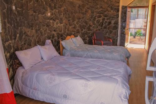拉利贝拉Lalibela Hidmo Cozy Place的一间卧室设有两张床和石墙