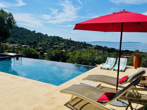 勒拉旺杜Villa Thalassa Art' B&B的游泳池旁的游泳池配有红色遮阳伞和椅子