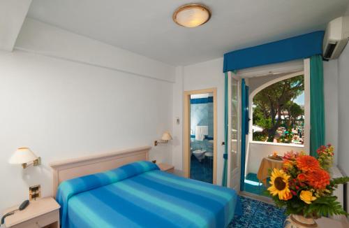 伊斯基亚赫莫萨海别墅酒店的一间卧室配有蓝色的床和镜子