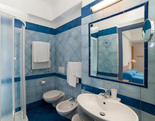 伊斯基亚赫莫萨海别墅酒店的蓝色瓷砖浴室设有水槽和卫生间