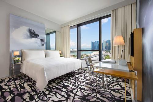 新加坡JW Marriott Hotel Singapore South Beach的卧室配有一张床、一张书桌和窗户。