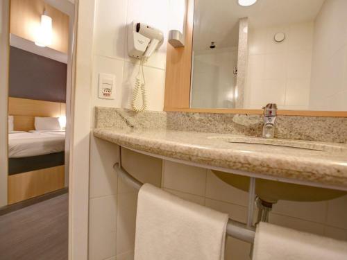 里约热内卢里约热内卢宜必思巴拉达蒂茹卡酒店的一间带水槽和镜子的浴室以及一张床