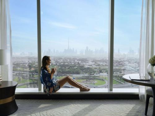 迪拜Sofitel Dubai The Obelisk的坐在建筑物窗户的顶端的女人