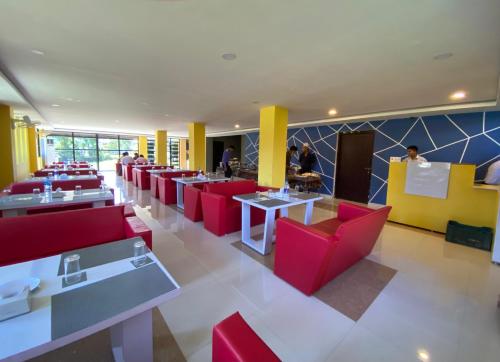 AtariaNamaste Hotel的一间设有红色桌椅的餐厅,可容纳众多客人。