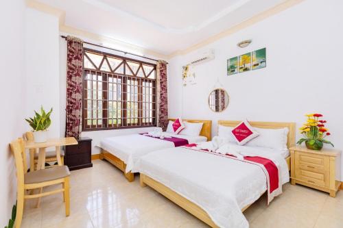 头顿Villa Hồ Bơi HOÀNG ĐỨC Trung Tâm BÃI SAU的一间卧室设有两张床、一张桌子和窗户。