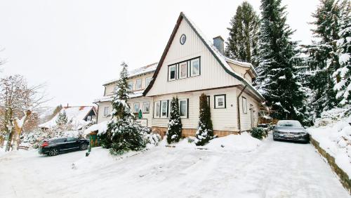 布劳恩拉格Hotel garni Am Hochwald的雪中的房子,车道上停有汽车