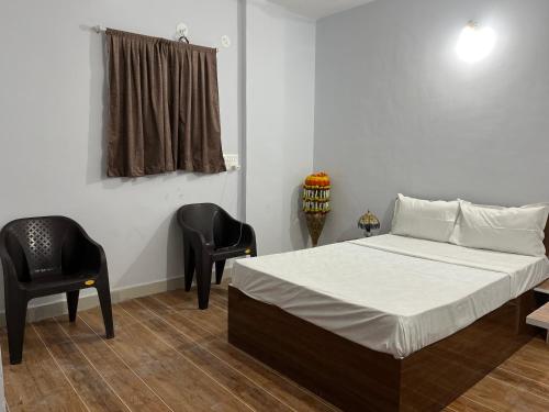 KharakvaslaLotus Guest House的一间卧室配有一张床和两张黑色椅子