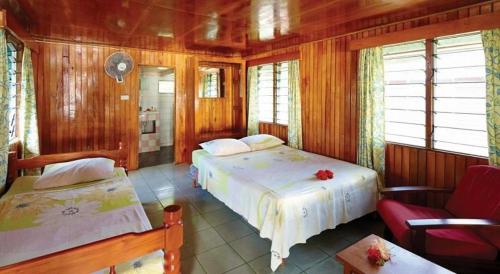 Naviti IslandKorovou Eco Lodge的一间卧室设有两张床、一把椅子和窗户。