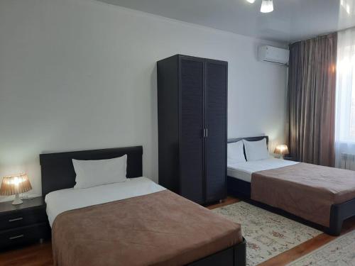 塔尔迪库尔干Апарт отель Welcome的酒店客房设有两张床和橱柜。