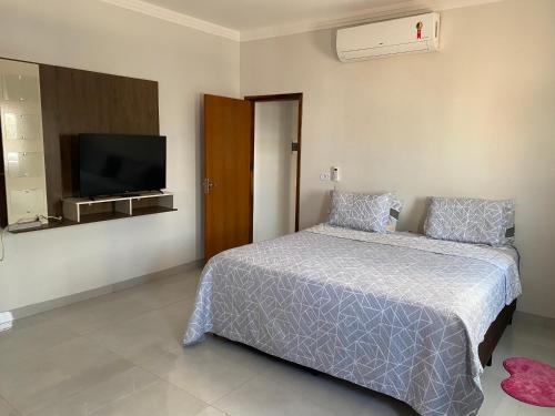 索里苏Apartamento Sorriso的一间卧室配有一张床和一台平面电视
