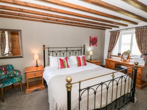 贝图瑟科伊德Orsedd Wen Cottage的一间卧室配有一张床、一张书桌和一个窗户。