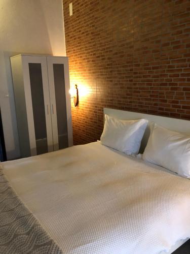 Casa BrancaCasa d'Aldeia的一张带白色枕头和砖墙的床