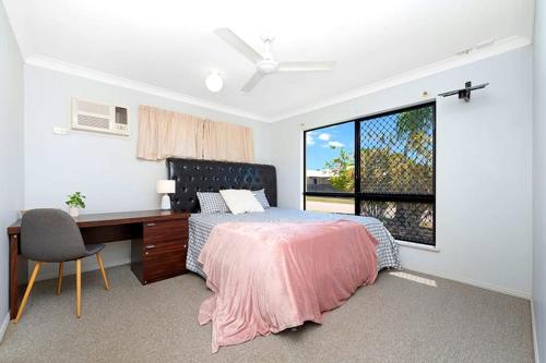 RossleaBeautiful Home stay in Townsville的一间卧室配有一张床、一张书桌和一个窗户。