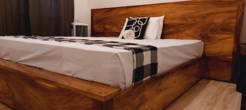 康提Ayubowan Holiday Home的一张大床,配有带枕头的木制床头板