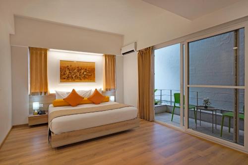 班加罗尔Nest By Rivido Apart Hotel, Bannerghatta road的一间卧室配有带橙色枕头的床和阳台