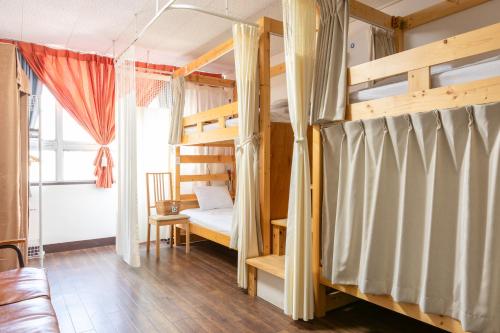 长崎Almas Guest House(アルマス）的一间带两张双层床和一张沙发的卧室