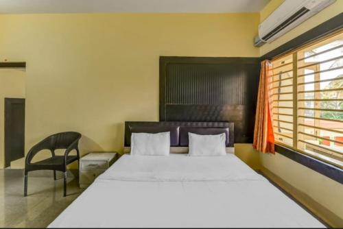 普里Goroomgo Hotel Moon Chakra Tirtha Road Puri - Excellent Stay with Family, Parking Facilities的卧室配有床、椅子和窗户。