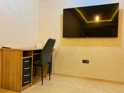 马拉喀什Beautiful apartment in gueliz with swimming pool的一张桌子、椅子和墙上的电视