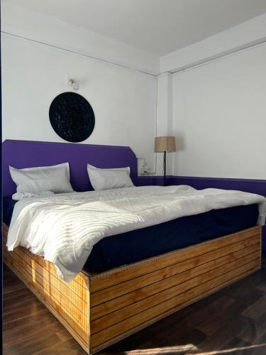 马拉里Tiny Spot Hostel的一间卧室配有一张大床和紫色床头板