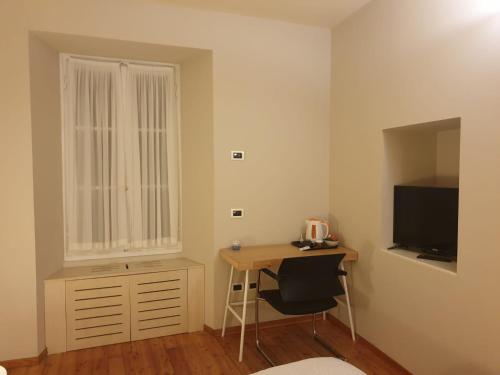 奥尔塔圣朱利奥皮克洛欧利娜酒店的小房间设有书桌和电视