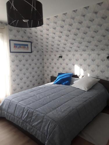 贝努维尔Chambres chez l habitant的一间卧室配有一张大床和灰色的被子