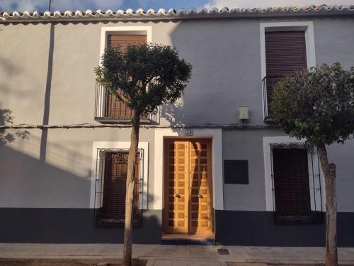 巴尔德佩尼亚斯Casa Rural con Estilo Valdepeñas的白色的房子,有一扇门和一棵树