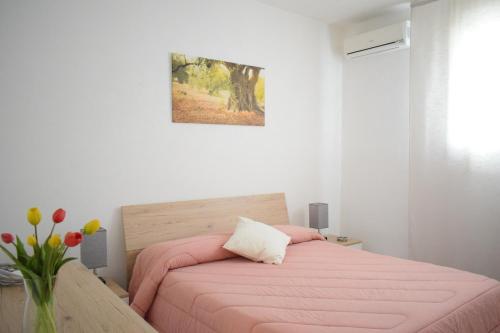 卡利亚里La Casa del Carrubo的卧室配有粉红色的床和花瓶