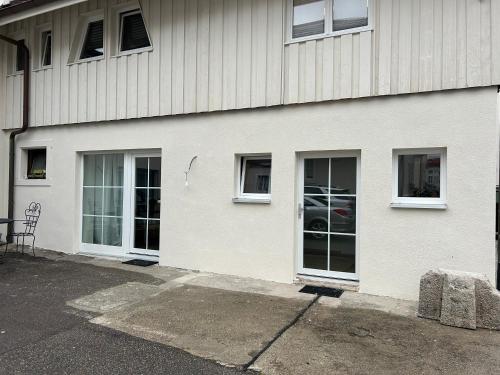 莱茵费尔登Boardinghouse Rheinfelden 1的白色的建筑,设有三扇窗户和椅子