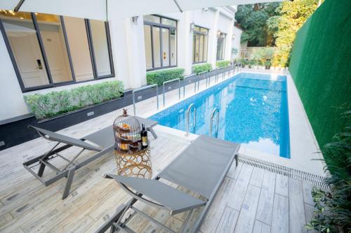海防Le Haute Hotel Hai Phong的房屋旁的游泳池配有桌椅